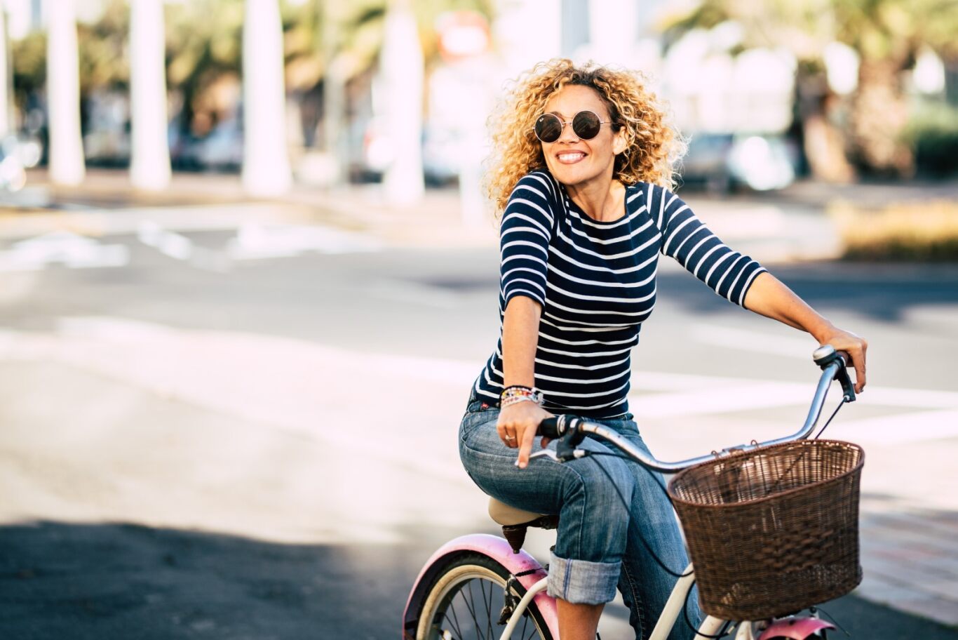 Lady in striped shirt riding a bike with basket